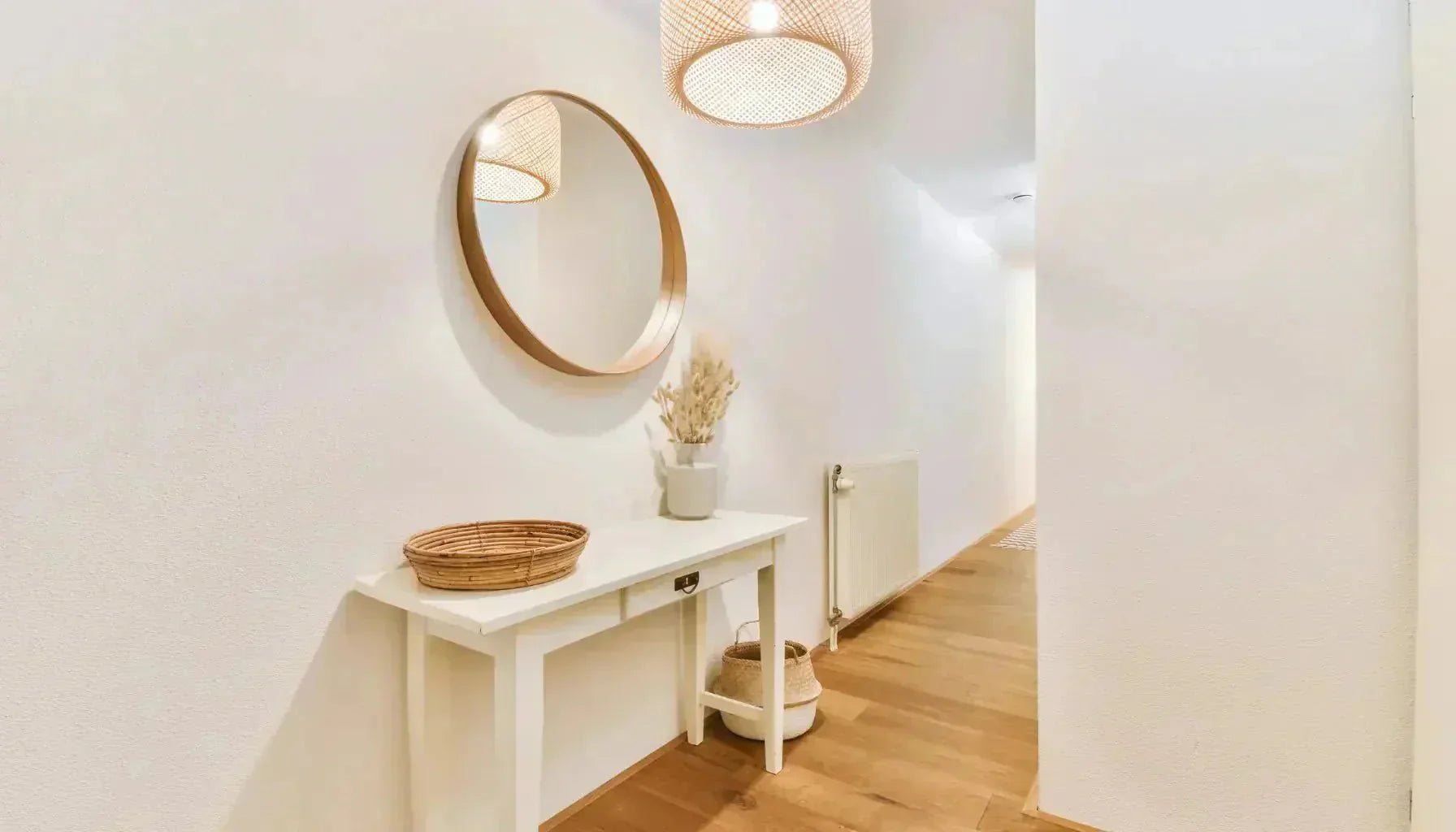 Miroir au cadre rond placé dans une entrée étroite pour agrandir l'espace par reflet.