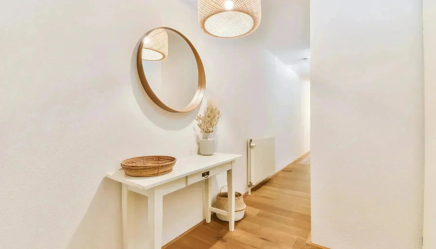 Miroir au cadre rond placé dans une entrée étroite pour agrandir l'espace par reflet.