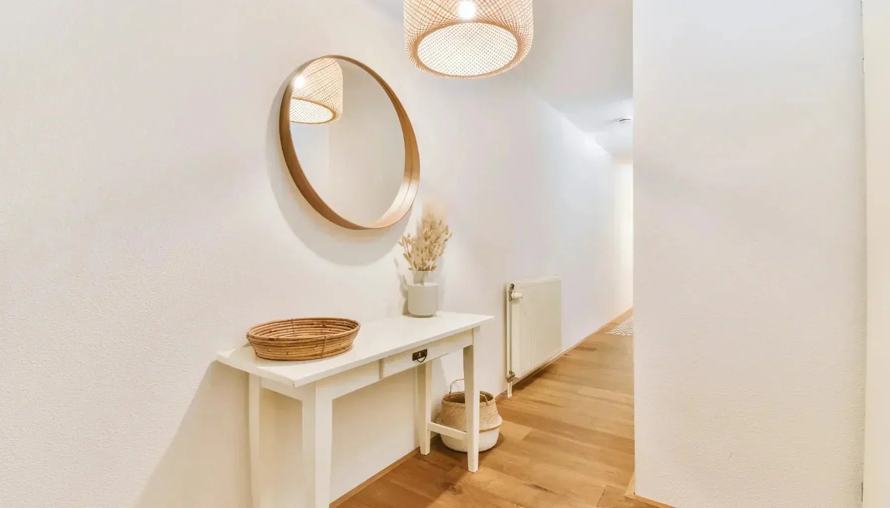 Miroir au cadre rond placé dans une entrée étroite pour agrandir l'espace par reflet.