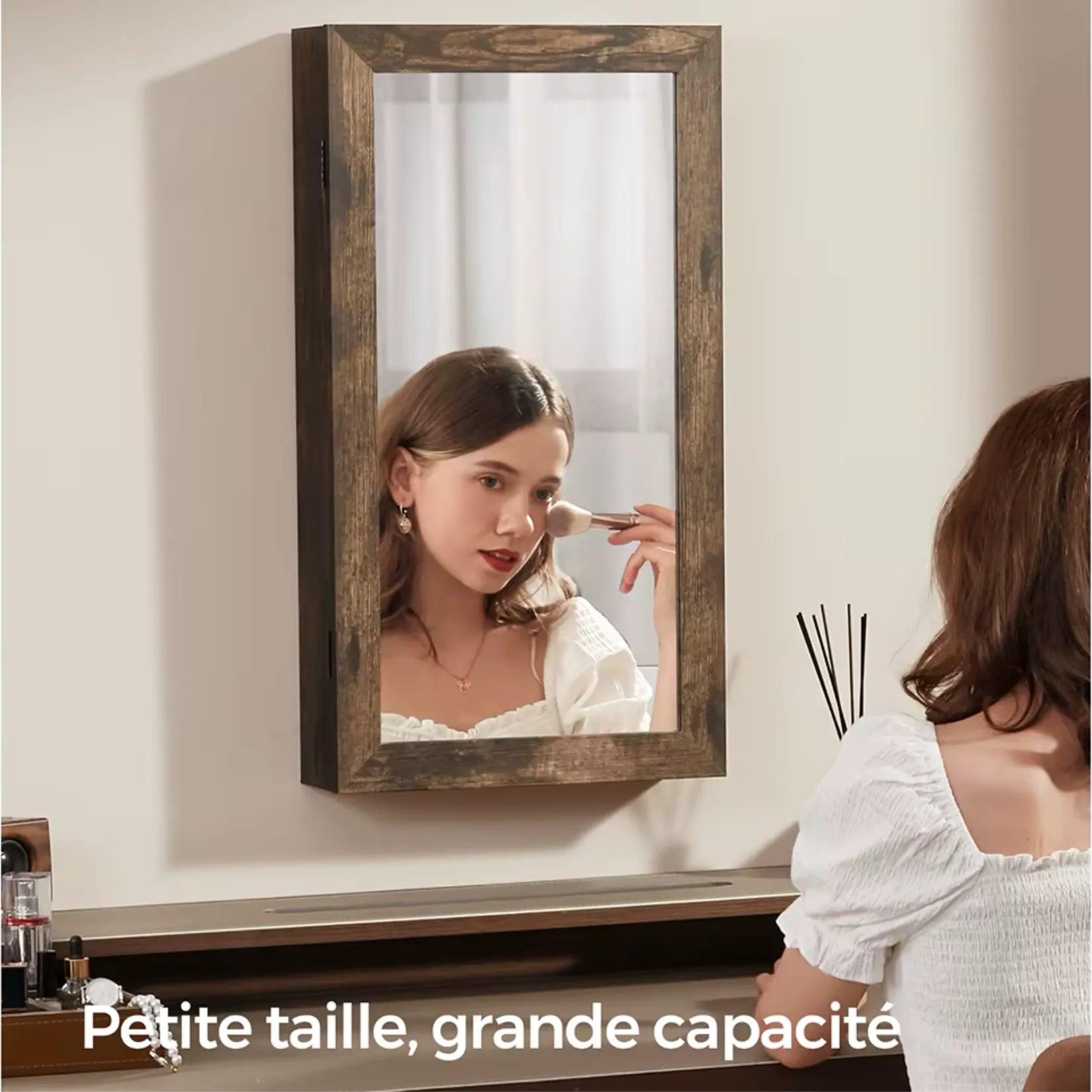 Femme se maquillant devant l’armoire à bijoux miroir bois suspendue.