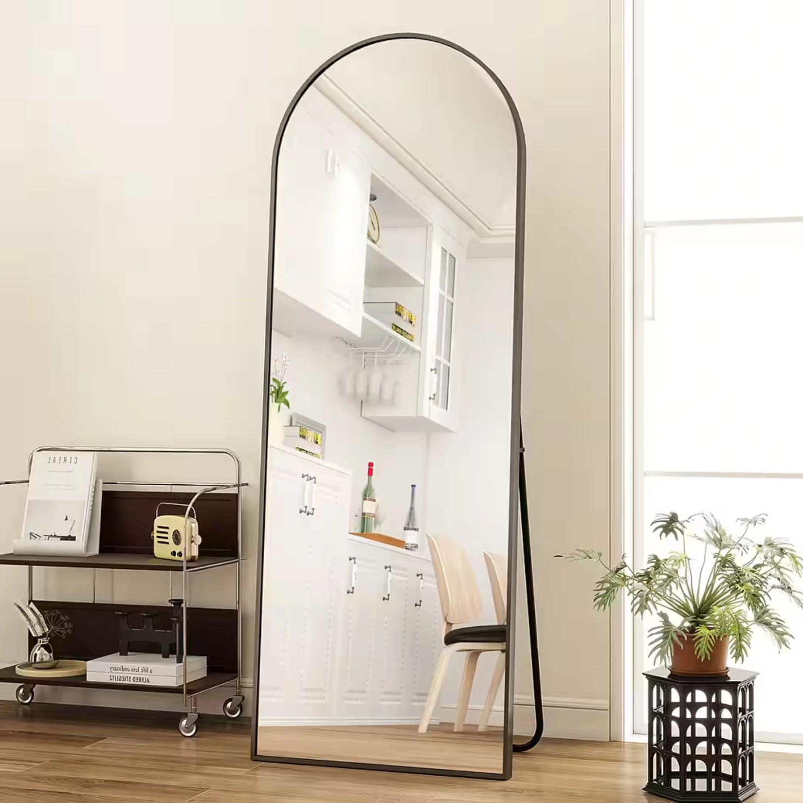 Grand Miroir Arrondi noir posé au sol, parfait pour agrandir visuellement l’espace et illuminer la pièce.