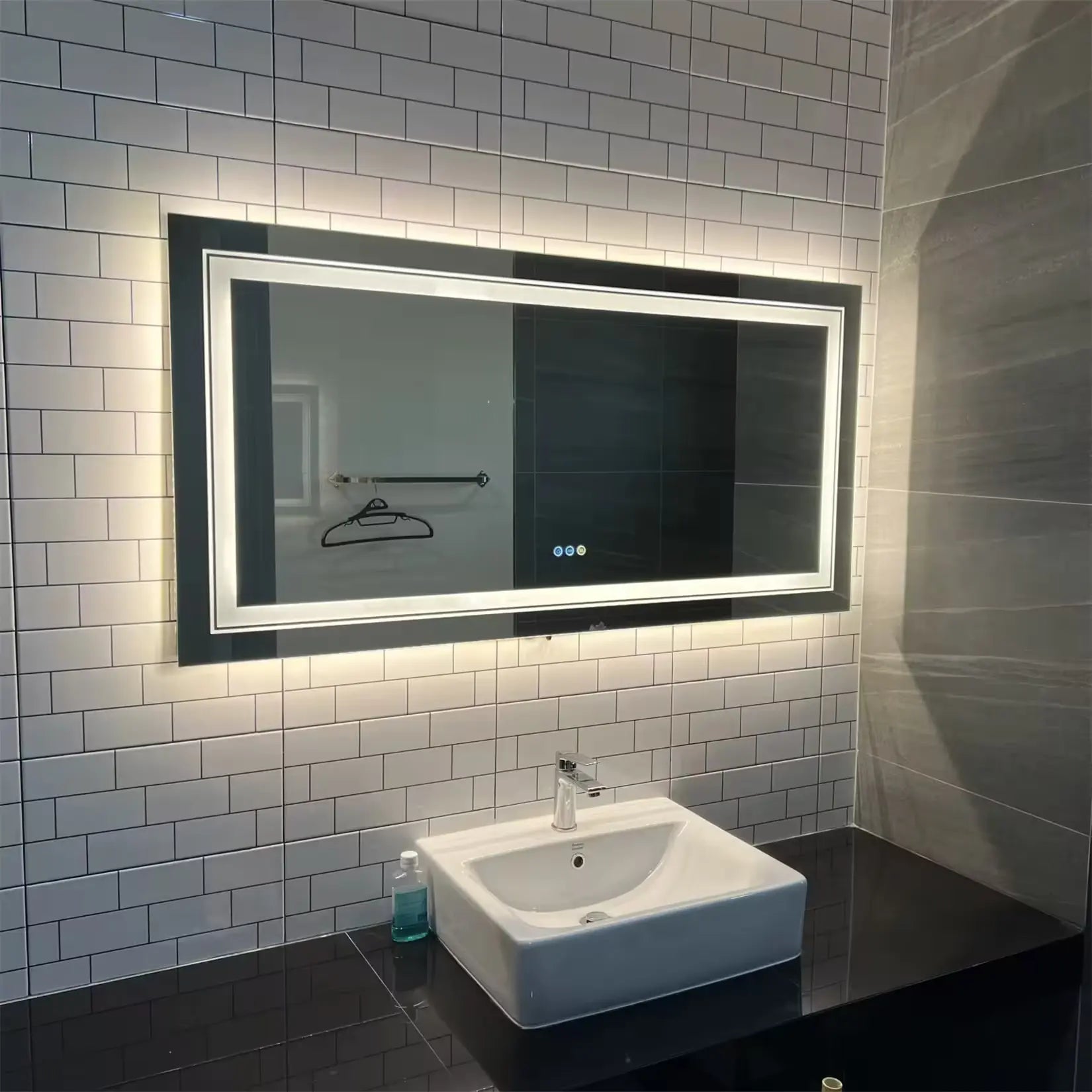 Grand miroir salle de bain LED installé sur carrelage métro blanc.