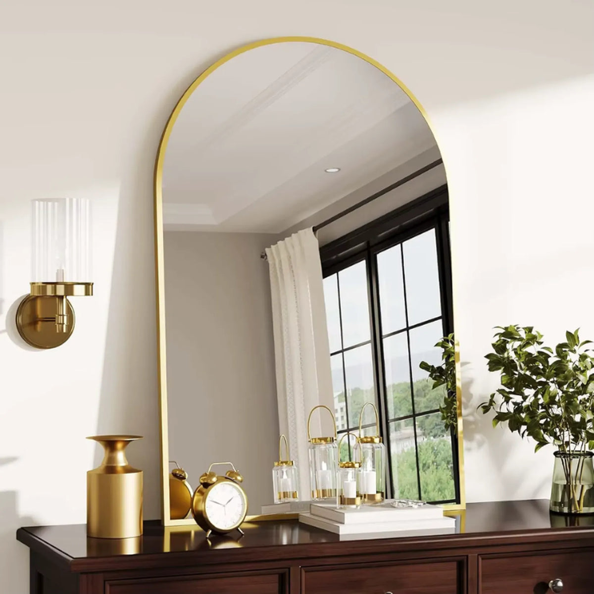 Miroir arche doré posé sur une commode dans une chambre.