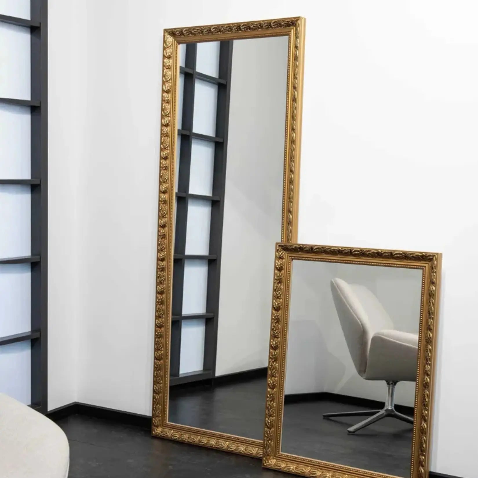 Miroir bois rectangulaire doré posé au sol contre un mur.