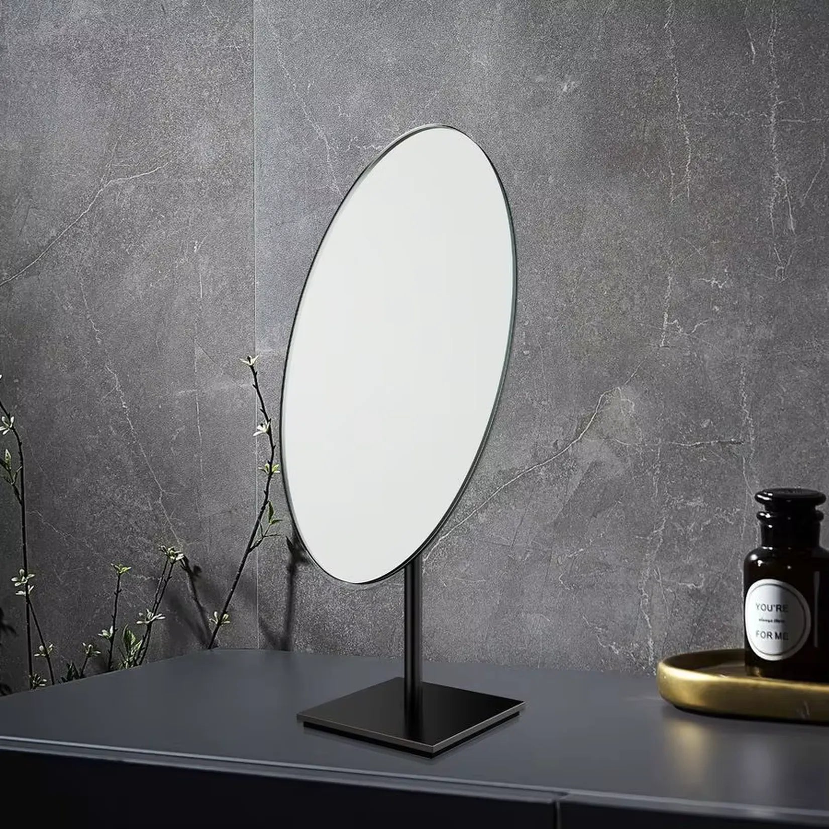 Miroir Bronze ovale sur pied posé sur meuble salle de bain ambiance moderne.