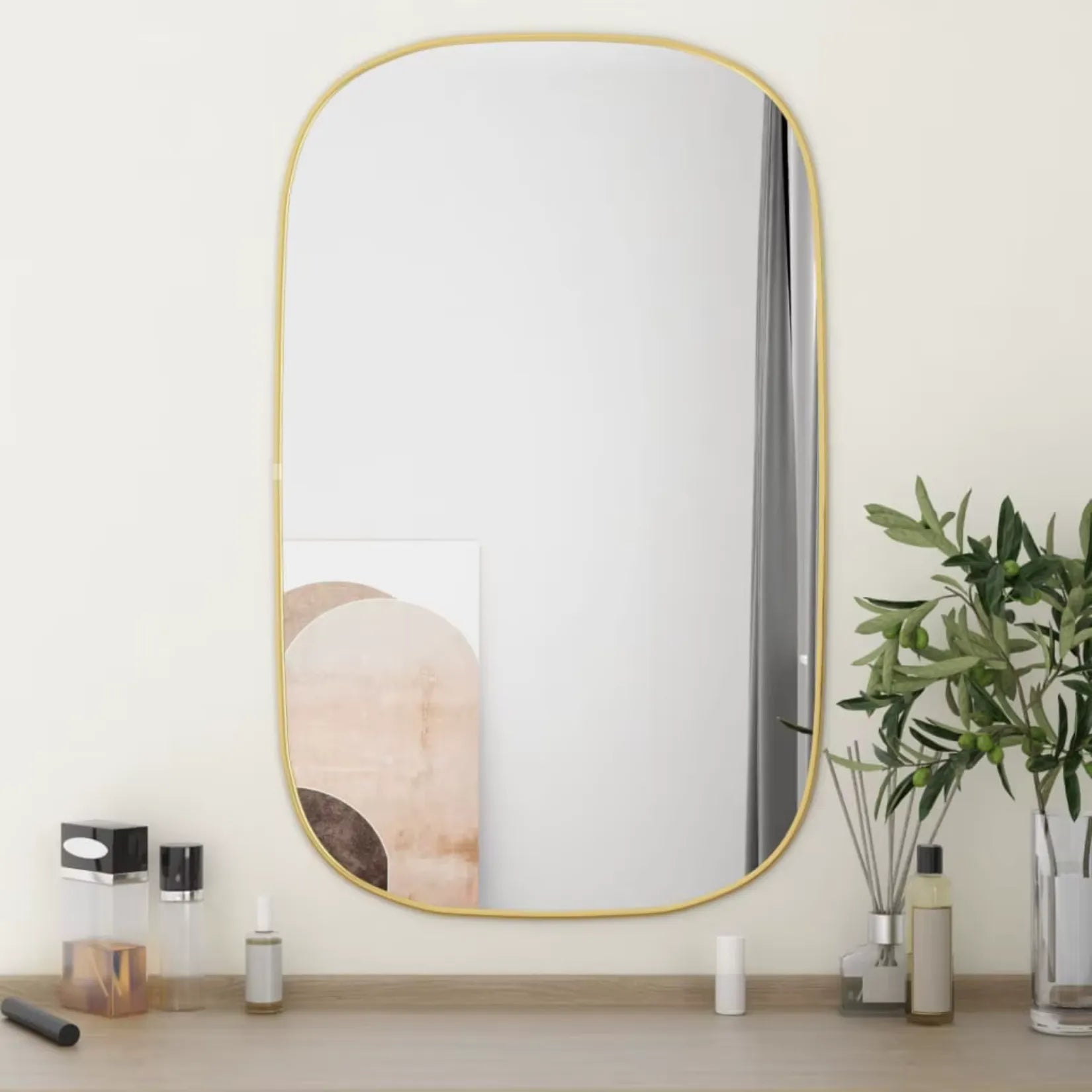 Miroir contour doré rectangulaire dans une déco naturelle sur table bois clair.