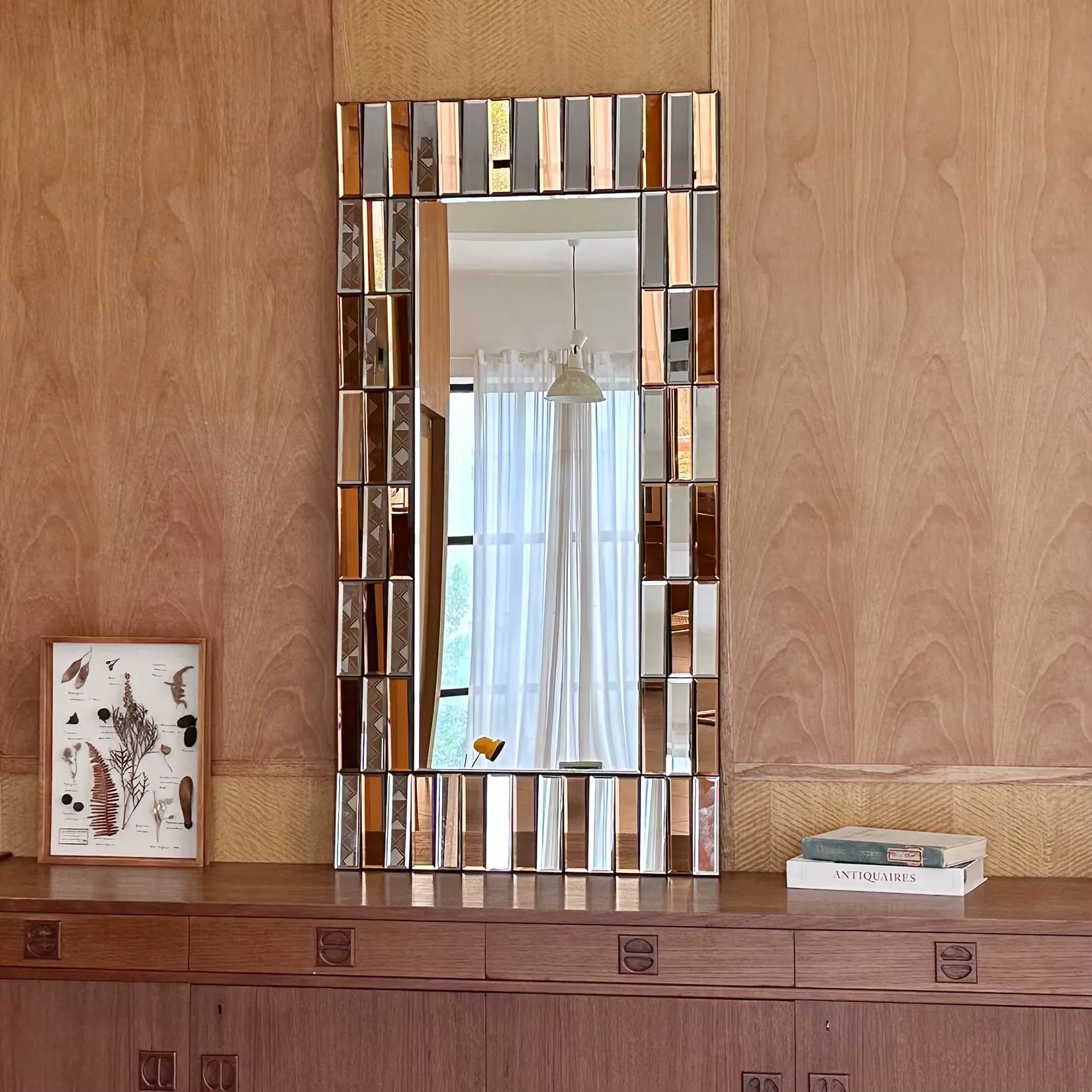 Miroir doré design accroché sur un mur en bois dans un décor naturel et chaleureux.