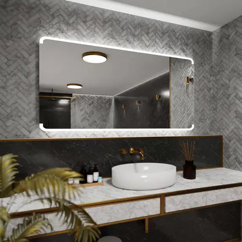 Miroir éclairant 180x80 dans une salle de bain en marbre à chevrons avec robinetterie dorée.