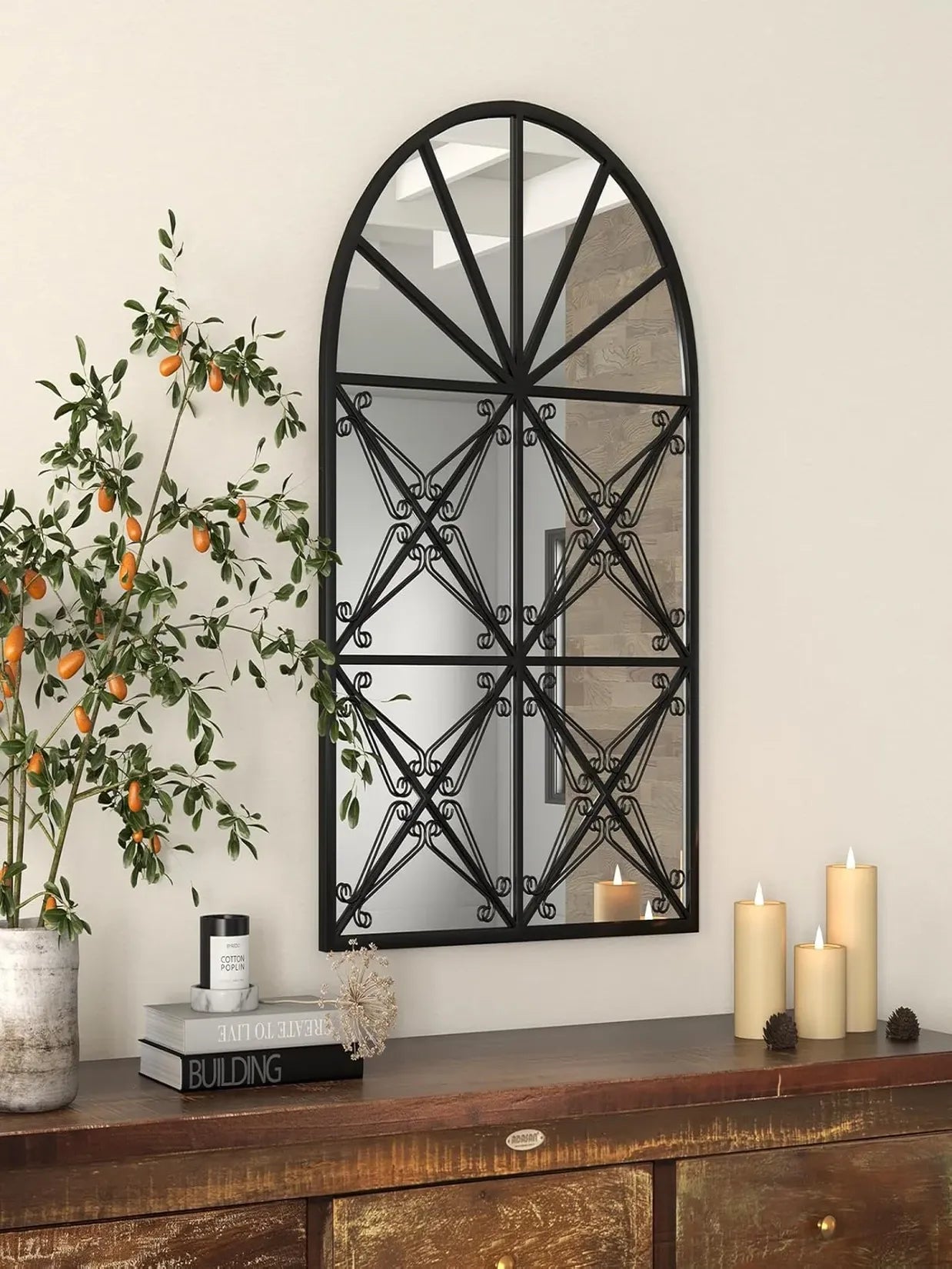 Miroir en fenêtre arche noir au-dessus d'une console en bois, décoration salon bougies.