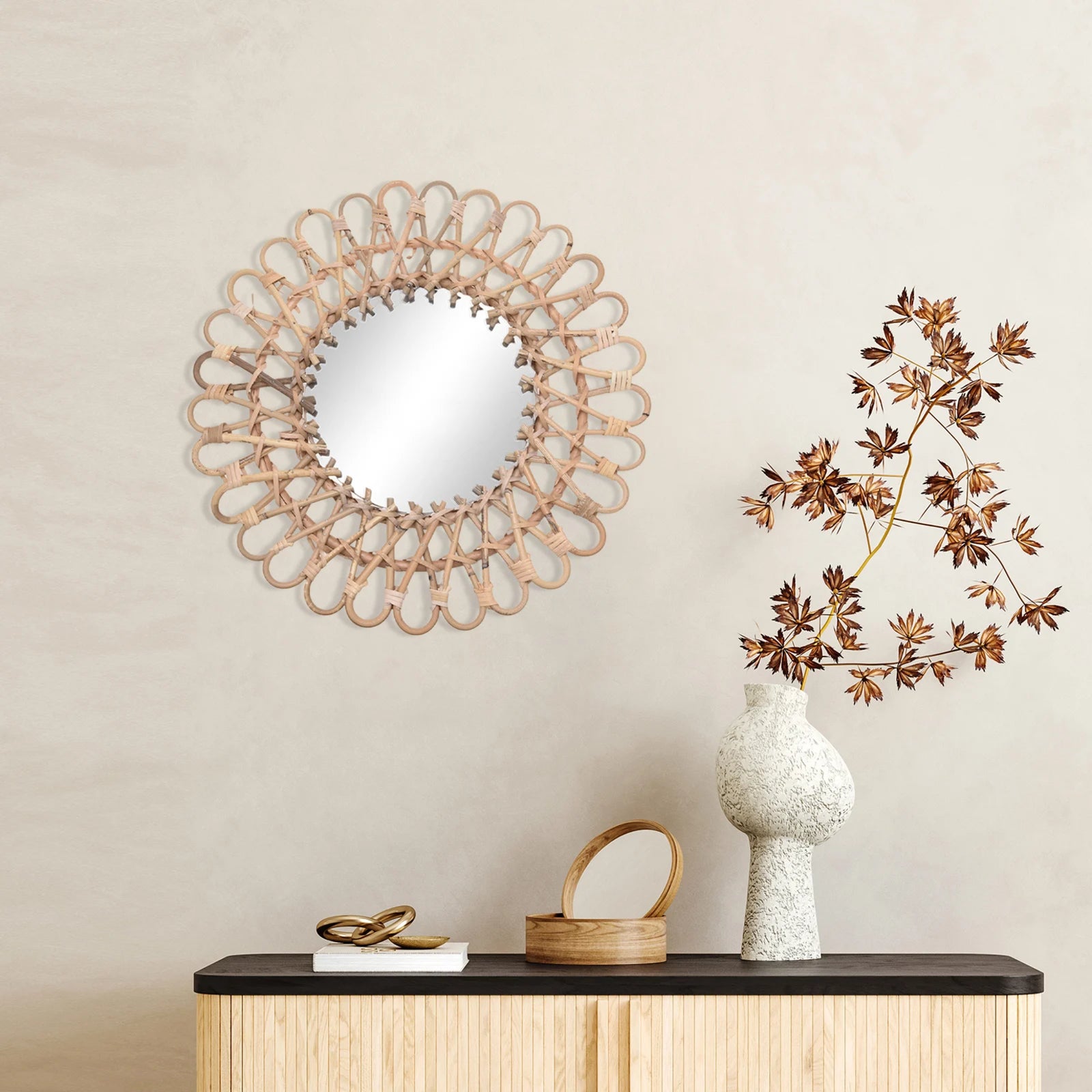 Miroir fleur rotin mis en valeur sur mur beige, au-dessus d’un buffet design naturel.