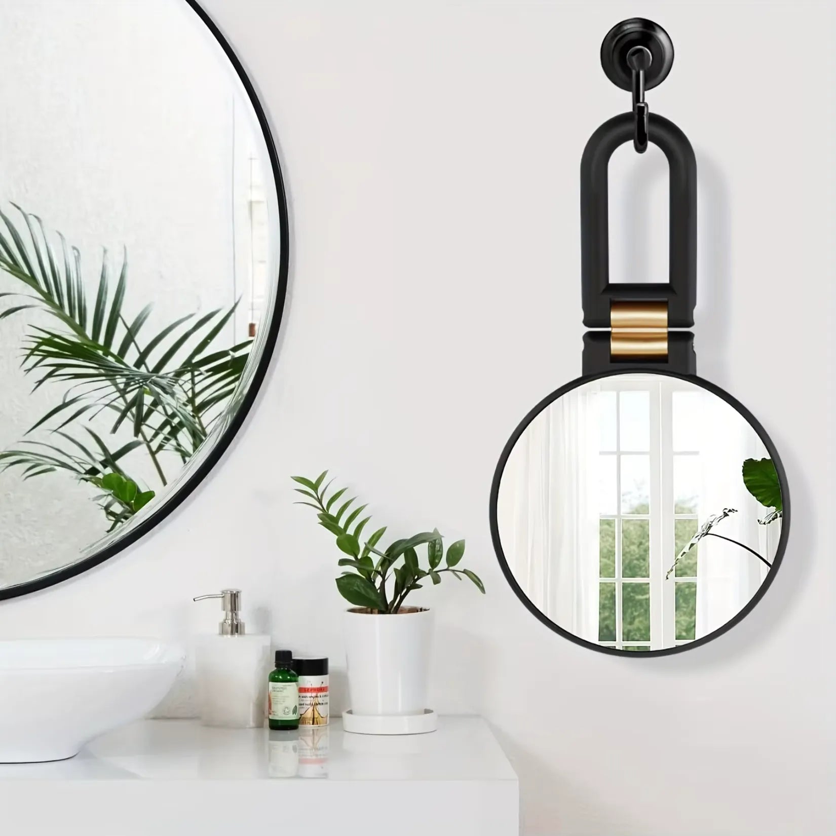 Miroir grossissant x50 suspendu par son anse à un crochet de salle de bain.
