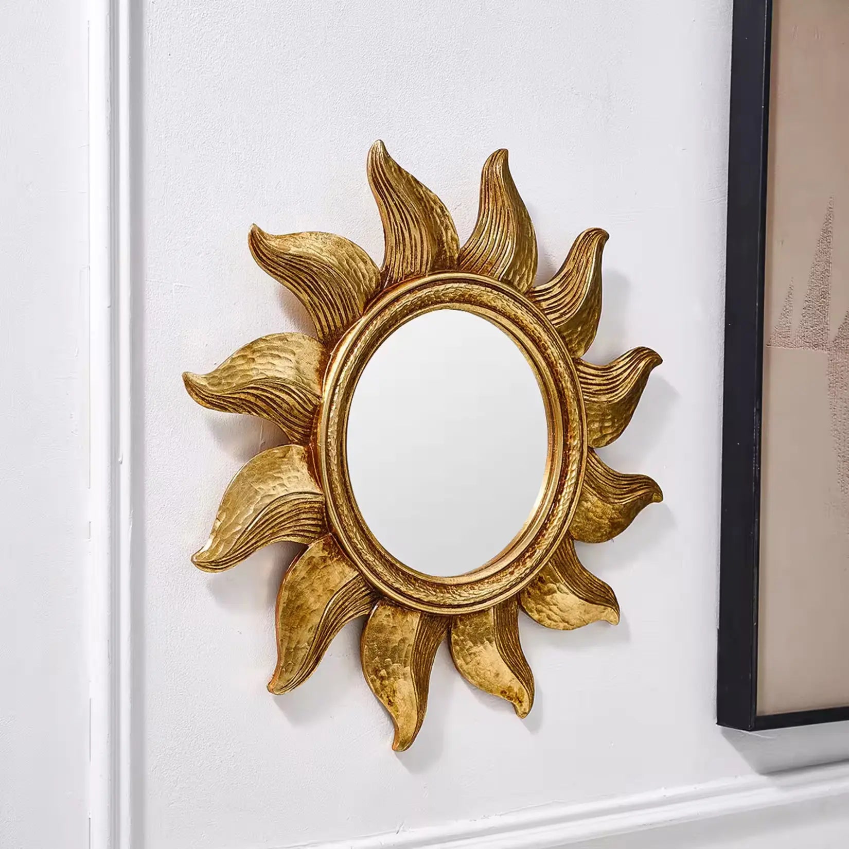 Miroir mural doré rond design soleil installé sur mur blanc décoration élégante.
