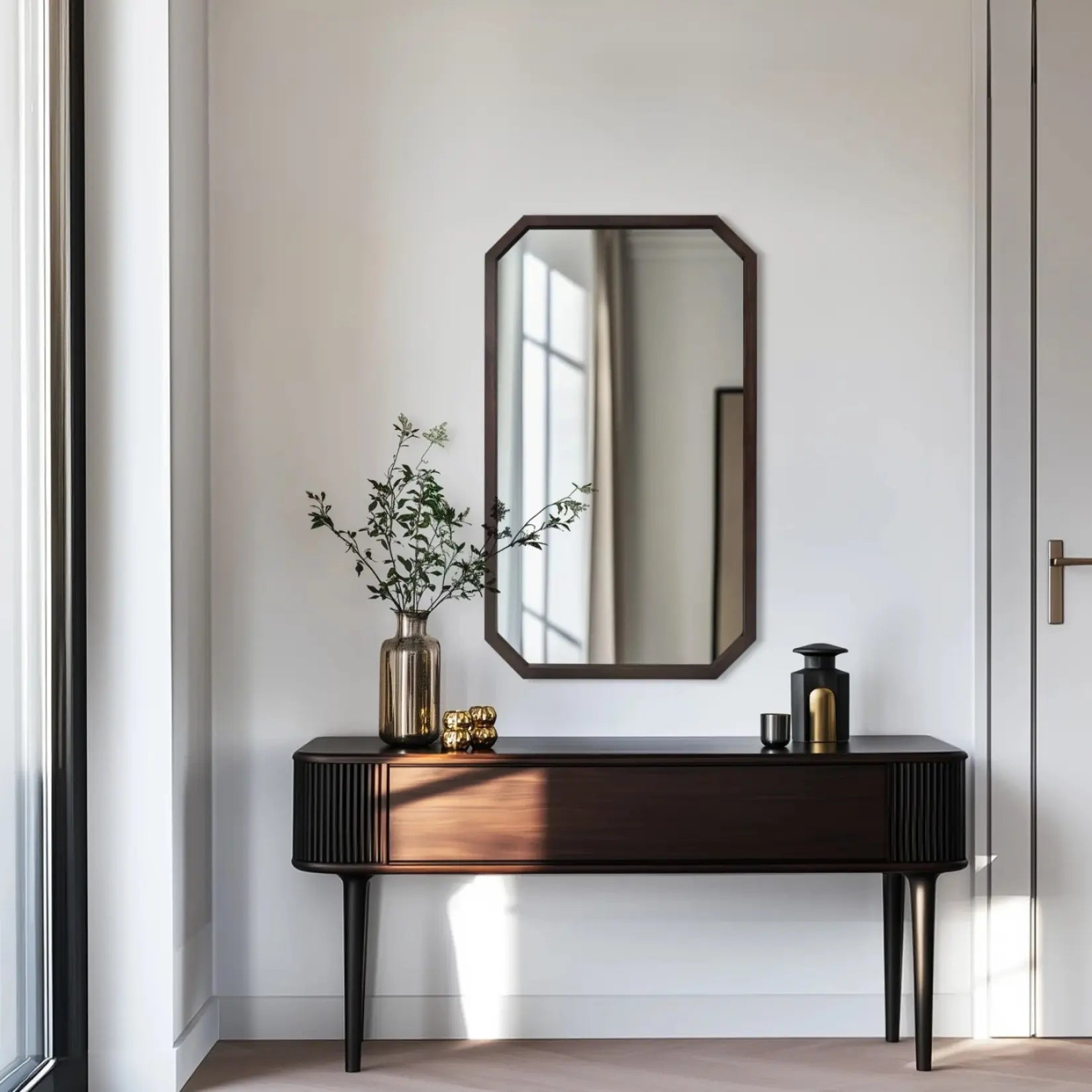 Miroir octogonal en bois noir au-dessus d’une console dans une entrée lumineuse.