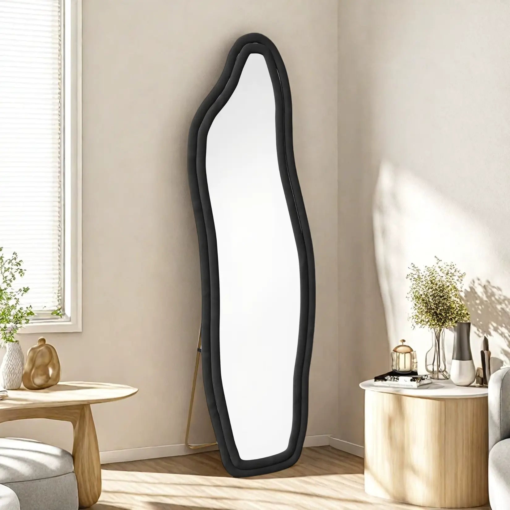 Miroir organique noir dans un coin lumineux avec mobilier clair et déco végétale.