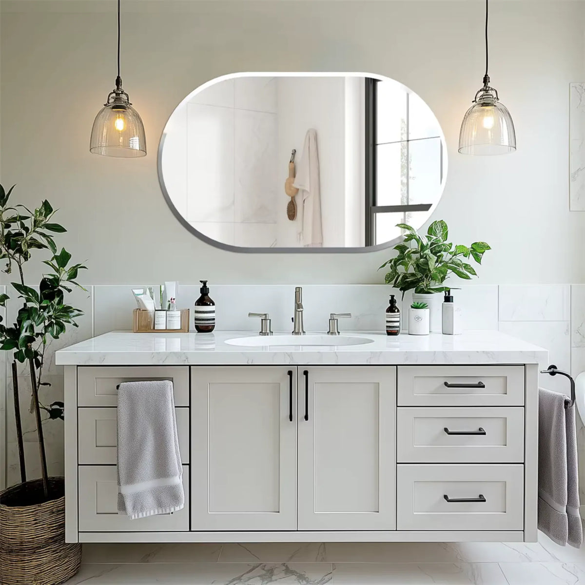 Miroir ovale en capsule à l'horizontale au-dessus d'une vasque blanche.