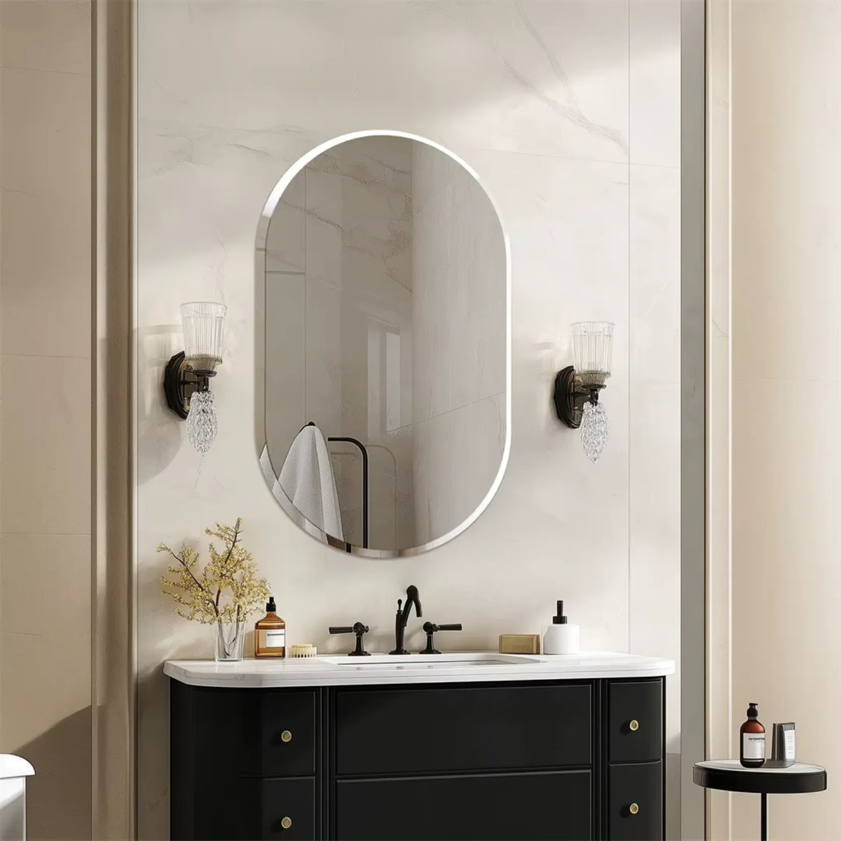 Miroir ovale à bords biseautés dans une salle de bain au mur marbré.