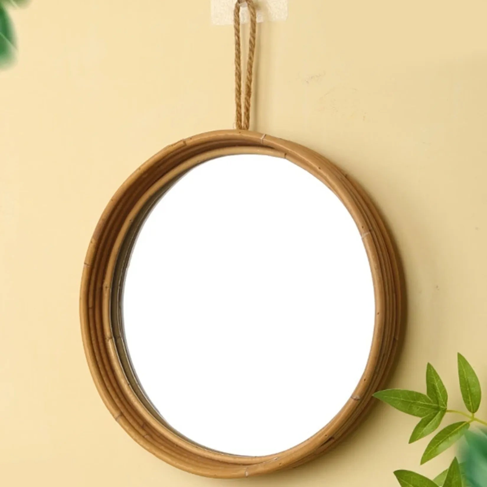Miroir rond rotin accroché au mur vue légèrement de côté.