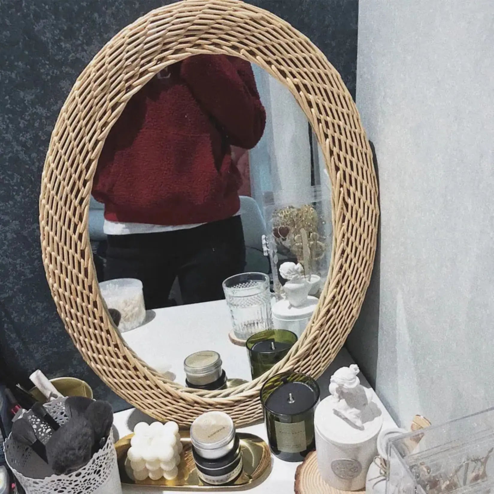 Miroir Rotin Ovale utilisé en coiffeuse sur une table décorée de bougies et accessoires.