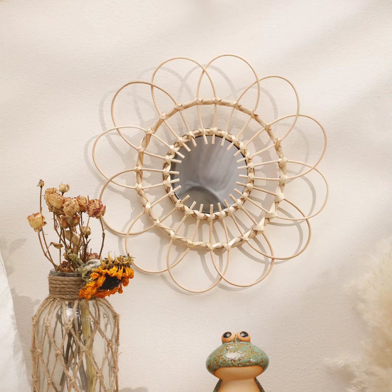 Miroir rotin soleil accroché sur un mur blanc, parfait pour une ambiance bohème chic.
