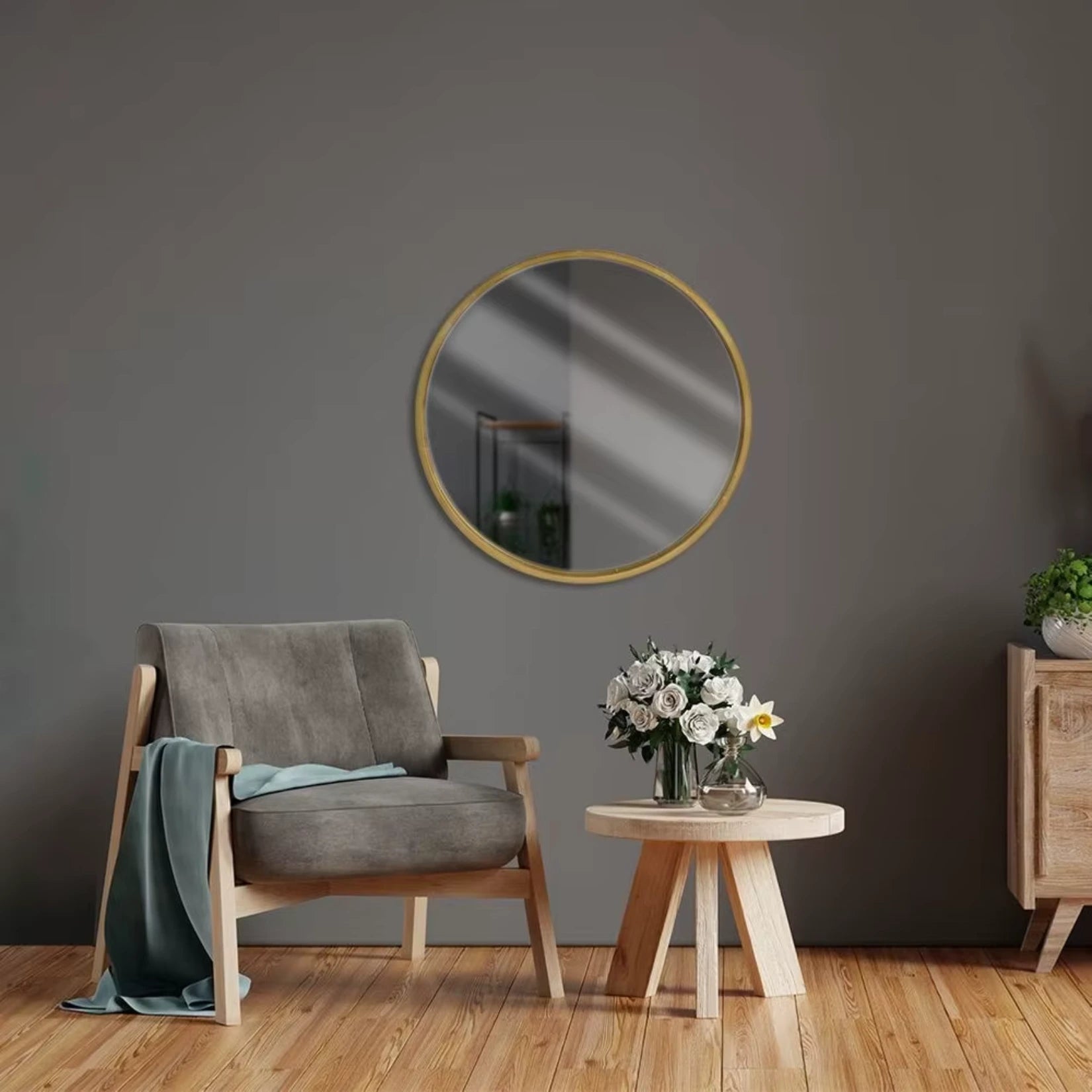Miroir scandinave rond avec cadre doré accroché sur un mur gris dans une ambiance épurée.