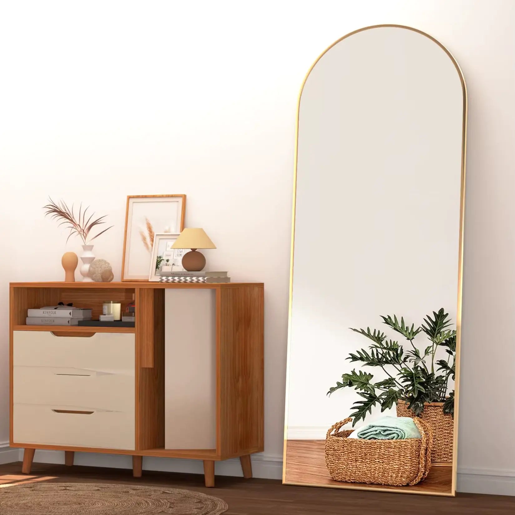 Miroir sur pied doré placé près d'une commode en bois et accessoires décoratifs.