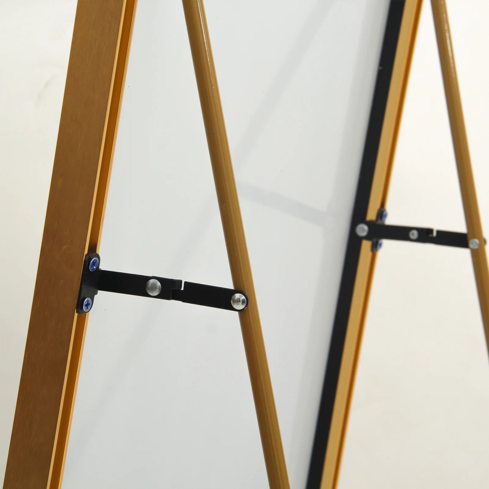 Détail du système rabattable du miroir sur pied doré, assurant stabilité et facilité de rangement.