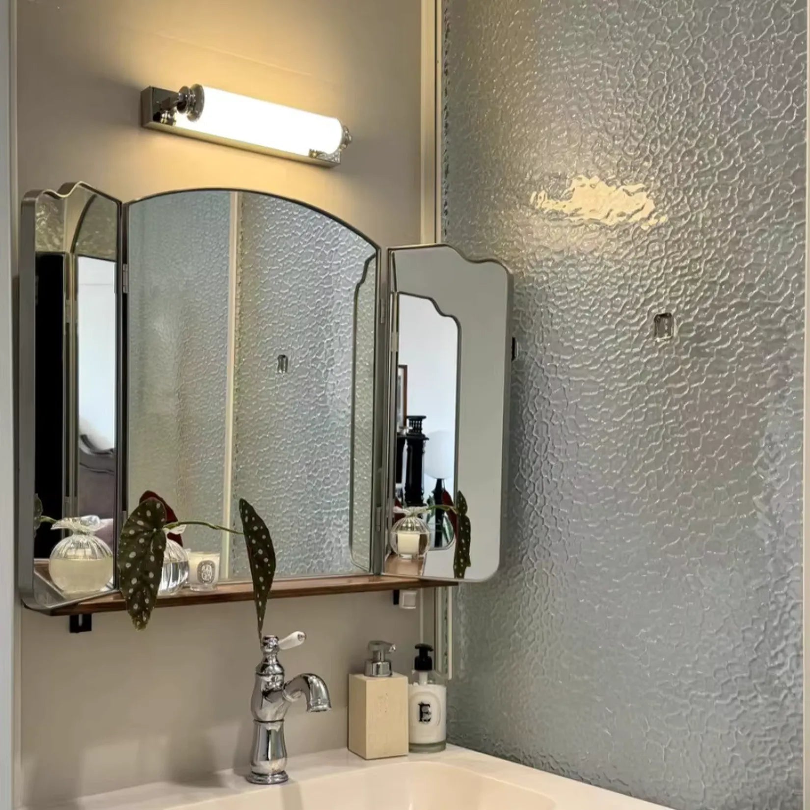 Miroir Triptyque Mural RÉGENCE argenté installé au-dessus d'un lavabo avec applique.