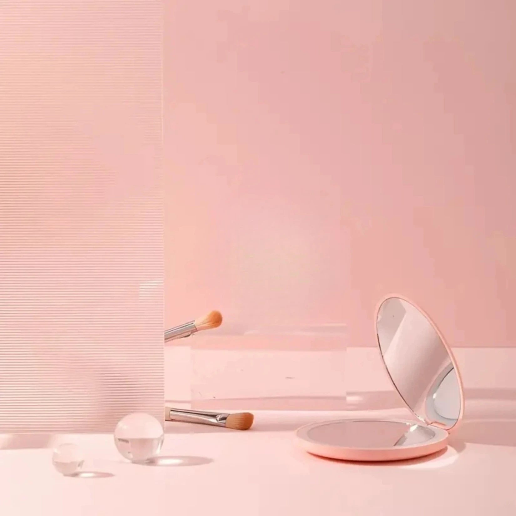 Petit miroir de poche entouré de pinceaux et éléments décoratifs.