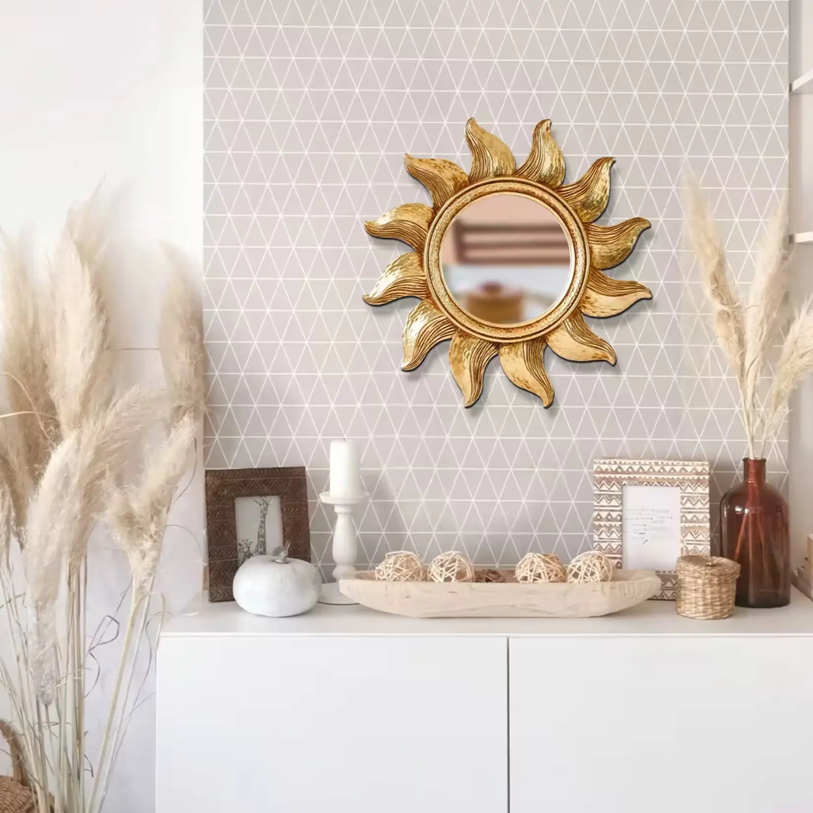 Petit miroir doré rond soleil dans décoration bohème moderne avec accessoires naturels.