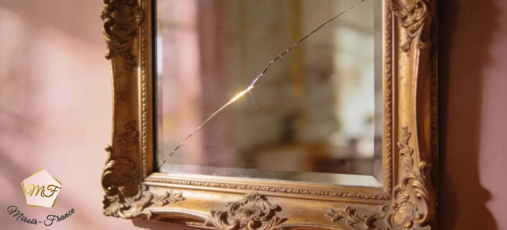 Miroir ancien au cadre doré orné avec une fine fêlure traversant le reflet.