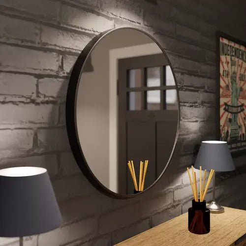 Gros plan sur le miroir rond noir de 60 cm avec un cadre en aluminium noir accroché dans une entrée