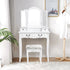 Coiffeuse grand tiroir 3 miroirs blanche avec tabouret dans une chambre lumineuse.