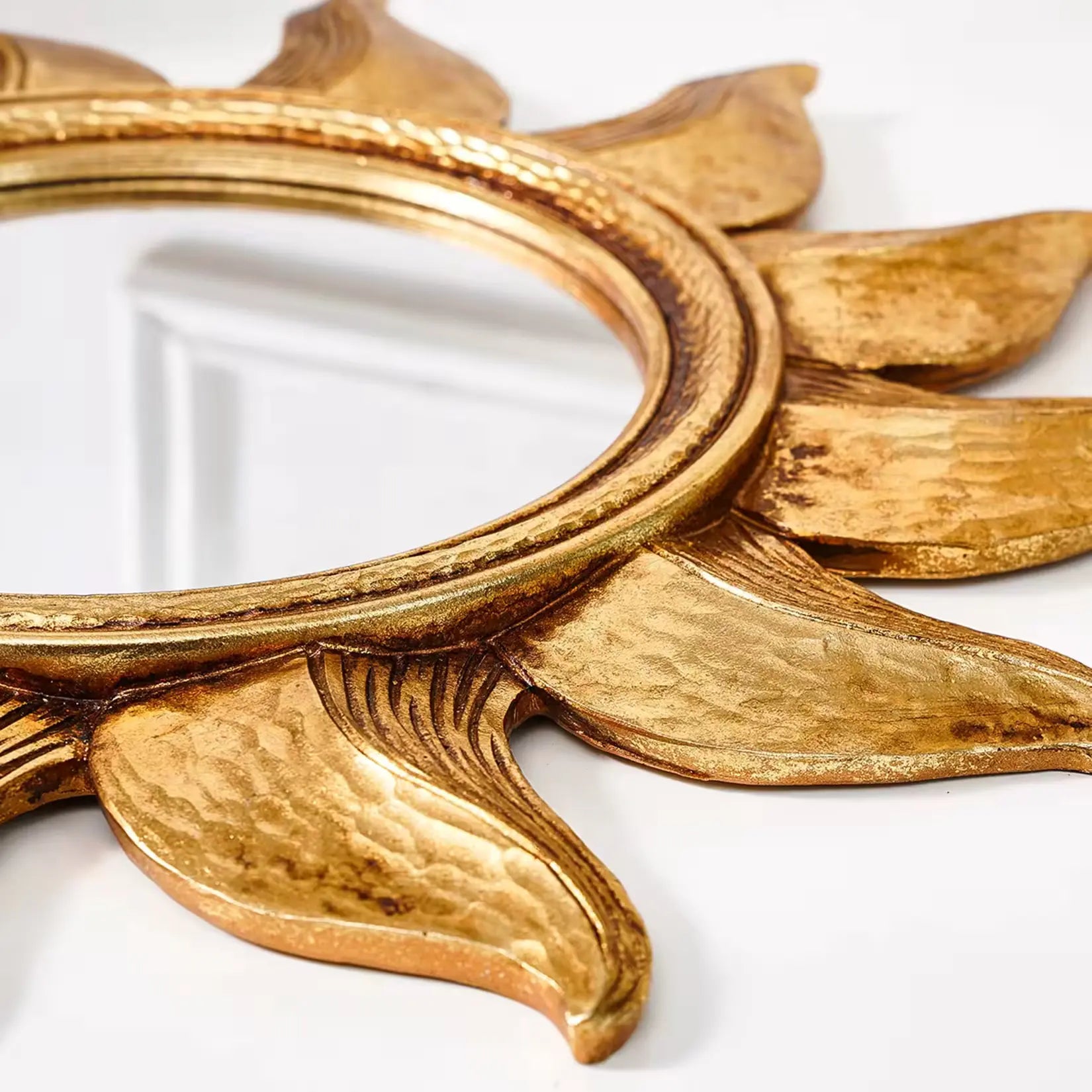 Détail de la finition dorée vieillie et des rayons sculptés du petit miroir rond soleil.