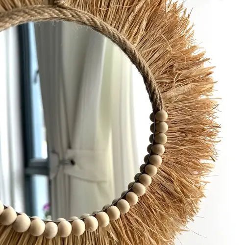 Détail du miroir en raphia et perles en bois pour une décoration unique.