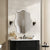 Grand miroir mural design dans une salle de bain avec meuble noir élégant.