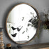 Grand miroir rond bois avec décor végétal en arrière-plan.