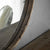 Grand miroir rond bois avec décor végétal en arrière-plan.