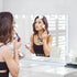 Femme réalisant un maquillage professionnel devant un miroir à maquillage lumineux.