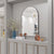 Miroir arqué placé au-dessus d'un bar raffiné avec décoration élégante.