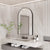 Miroir arqué avec cadre noir dans une salle de bain luxueuse au design contemporain.