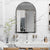 Miroir arqué avec un cadre noir dans une salle de bain urbaine au design en marbre.