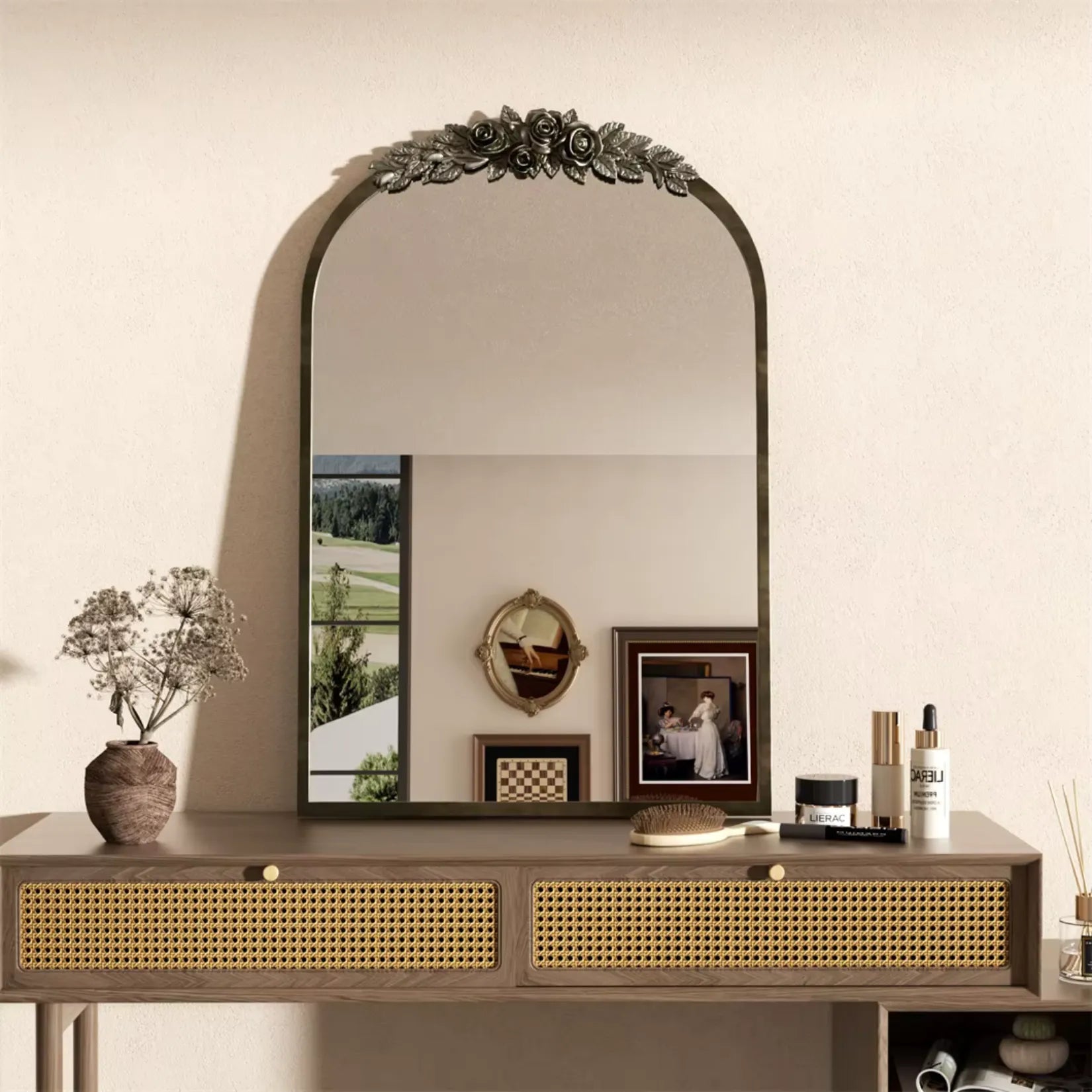 Un miroir baroque doré se dresse au-dessus d’une console à cannage dans un intérieur clair et épuré de style bohème chic.