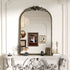 Miroir baroque doré accroché au-dessus d’une cheminée blanche sculptée dans un intérieur de style classique raffiné.