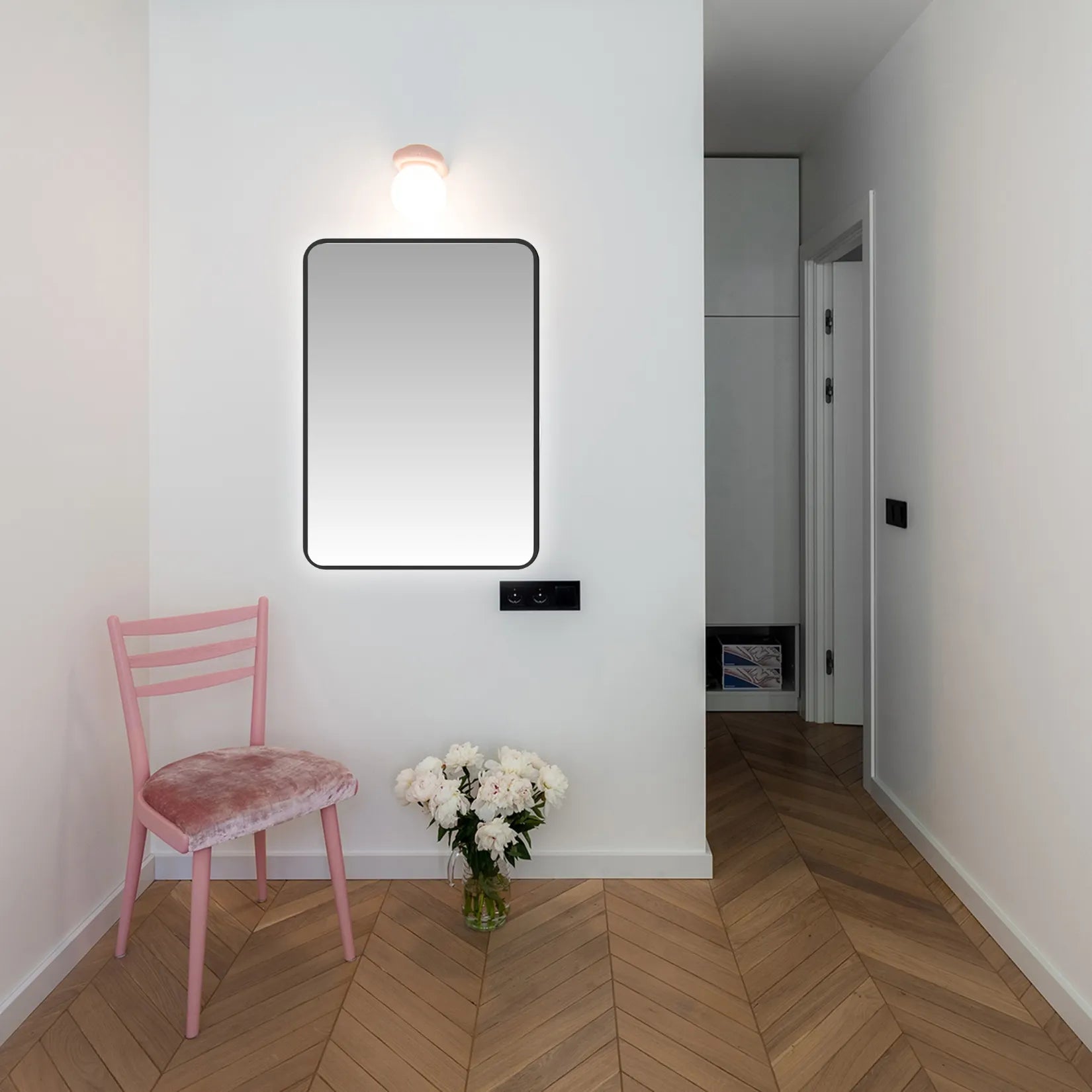 Miroir cadre noir rectangulaire dans une entrée blanche au sol en point de Hongrie.