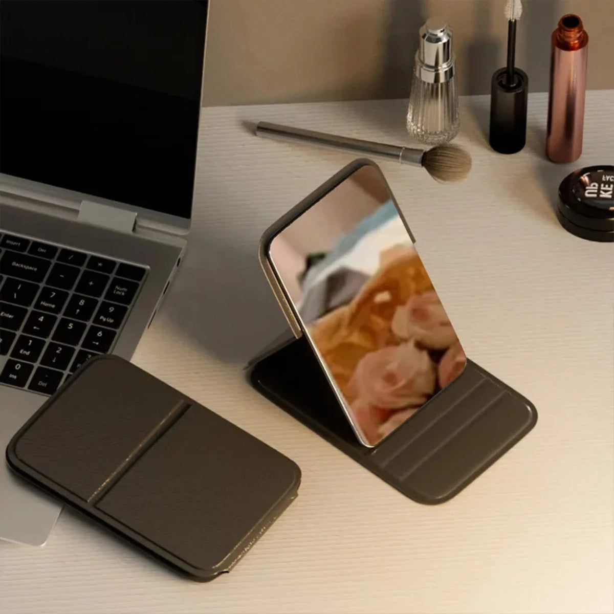 Miroir de poche noir pliable pratique sur un bureau moderne.