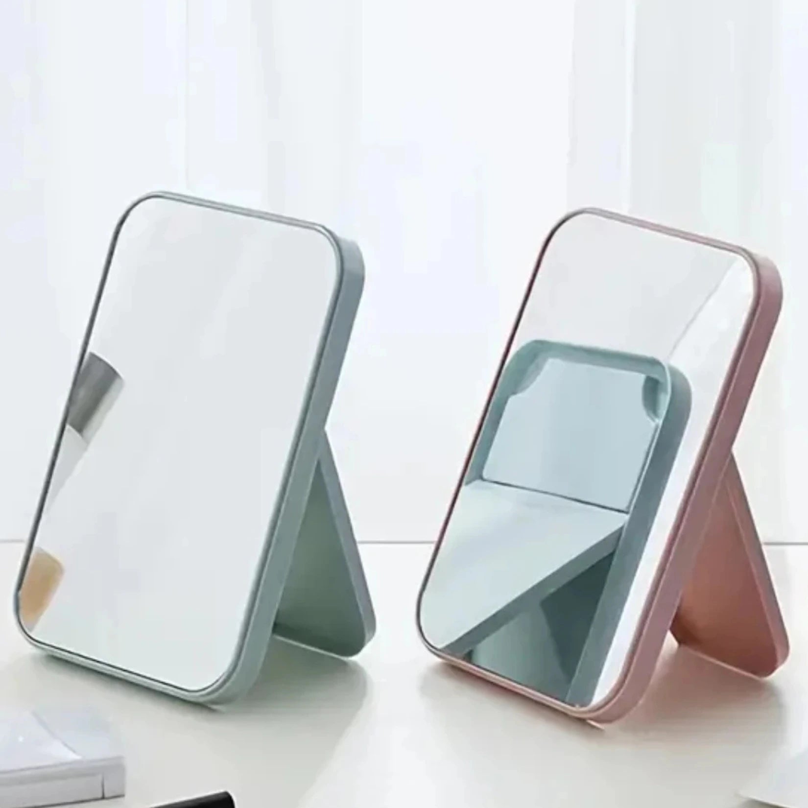 Deux miroirs de poche rectangulaires côte à côte, un gris et un rose, en position verticale.