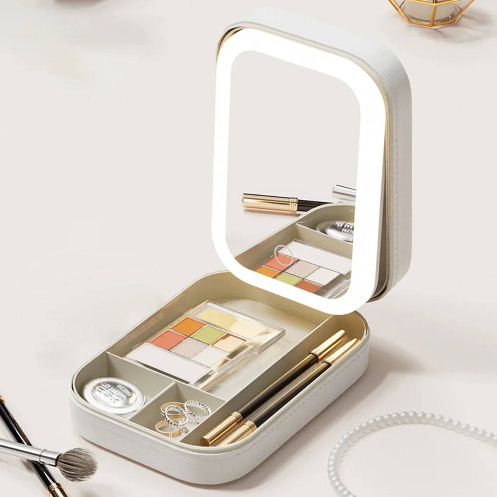 Miroir de sac LED blanc ouvert montrant le rangement divisé pour pinceaux, rouges à lèvres et bijoux.