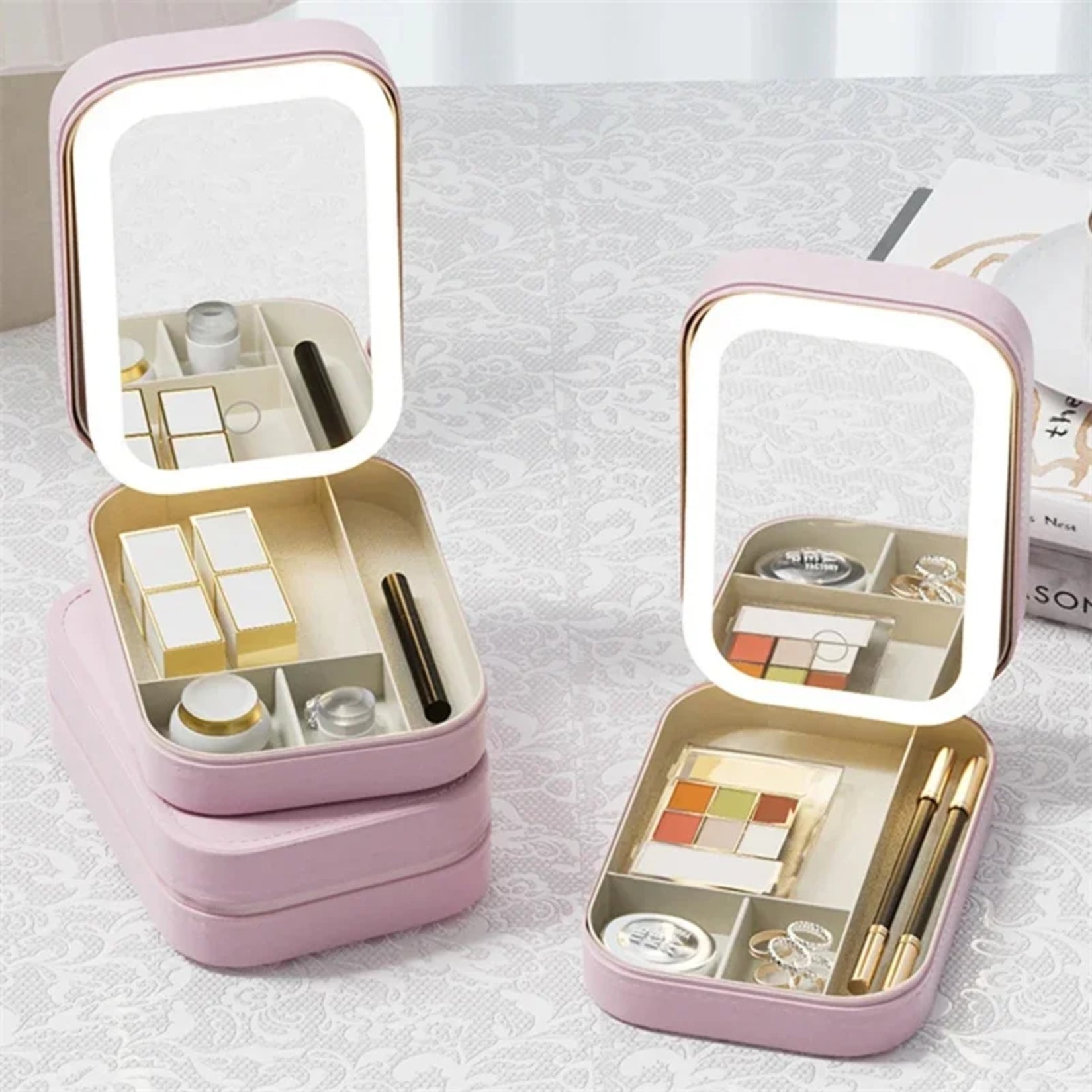 Miroir de sac LED rose avec rangement compartimenté, deux coffrets ouverts posés sur une table.