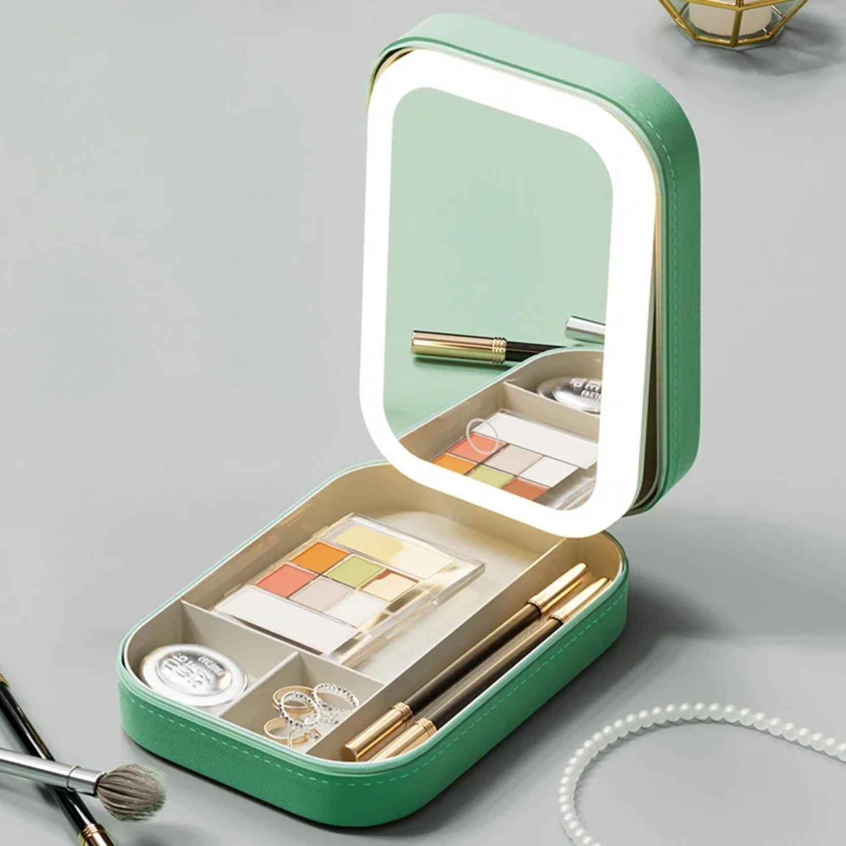 Miroir de sac LED beige émettant une lumière chaude, deux coffrets ouverts sur table avec accessoires.