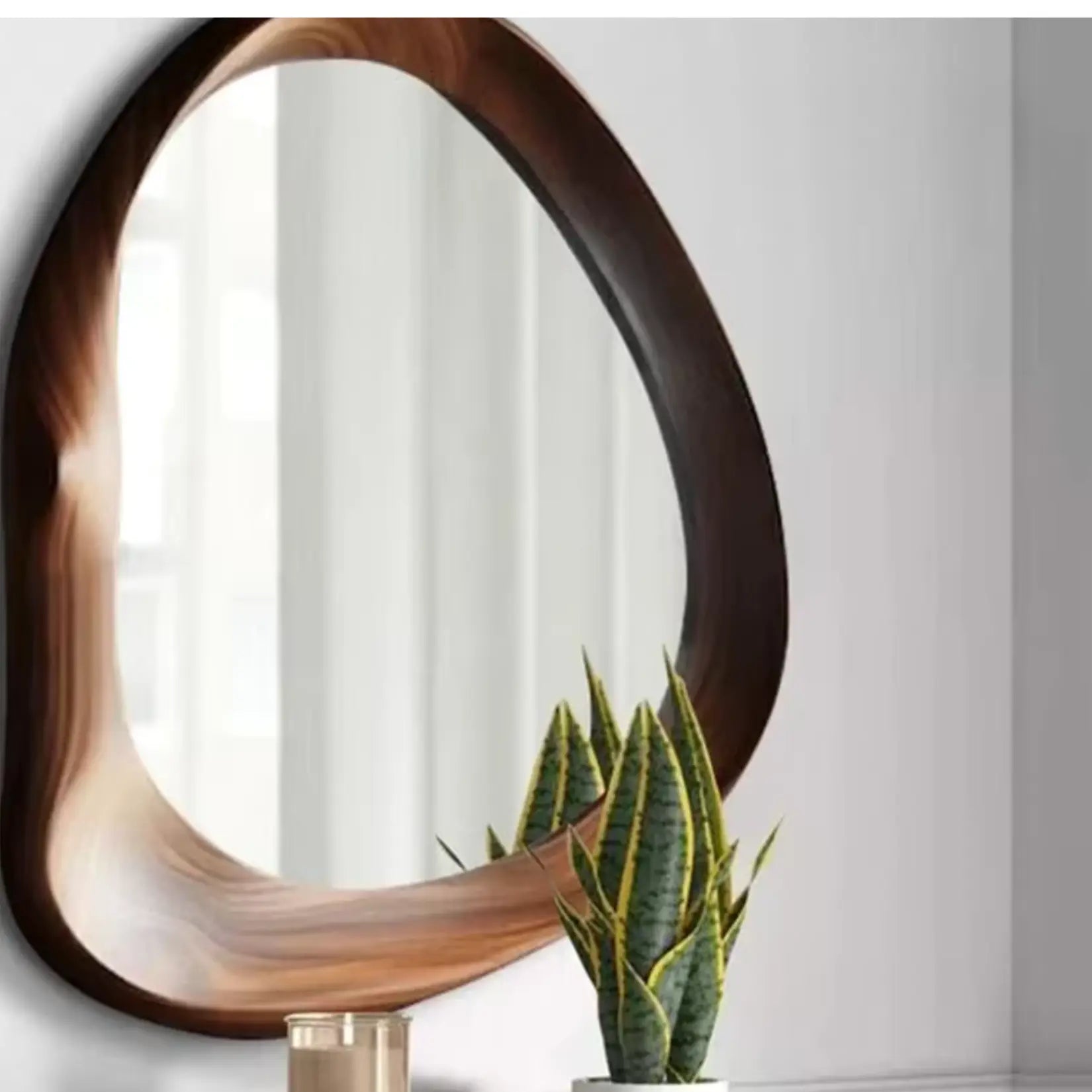 Miroir design bois avec plante décorative sur meuble blanc dans un intérieur lumineux.